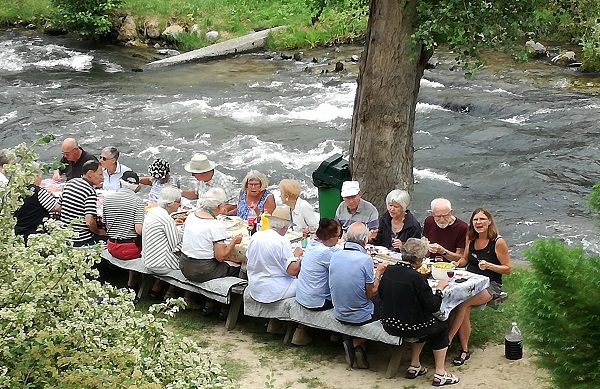 Gruppe spiser picnic ved floden